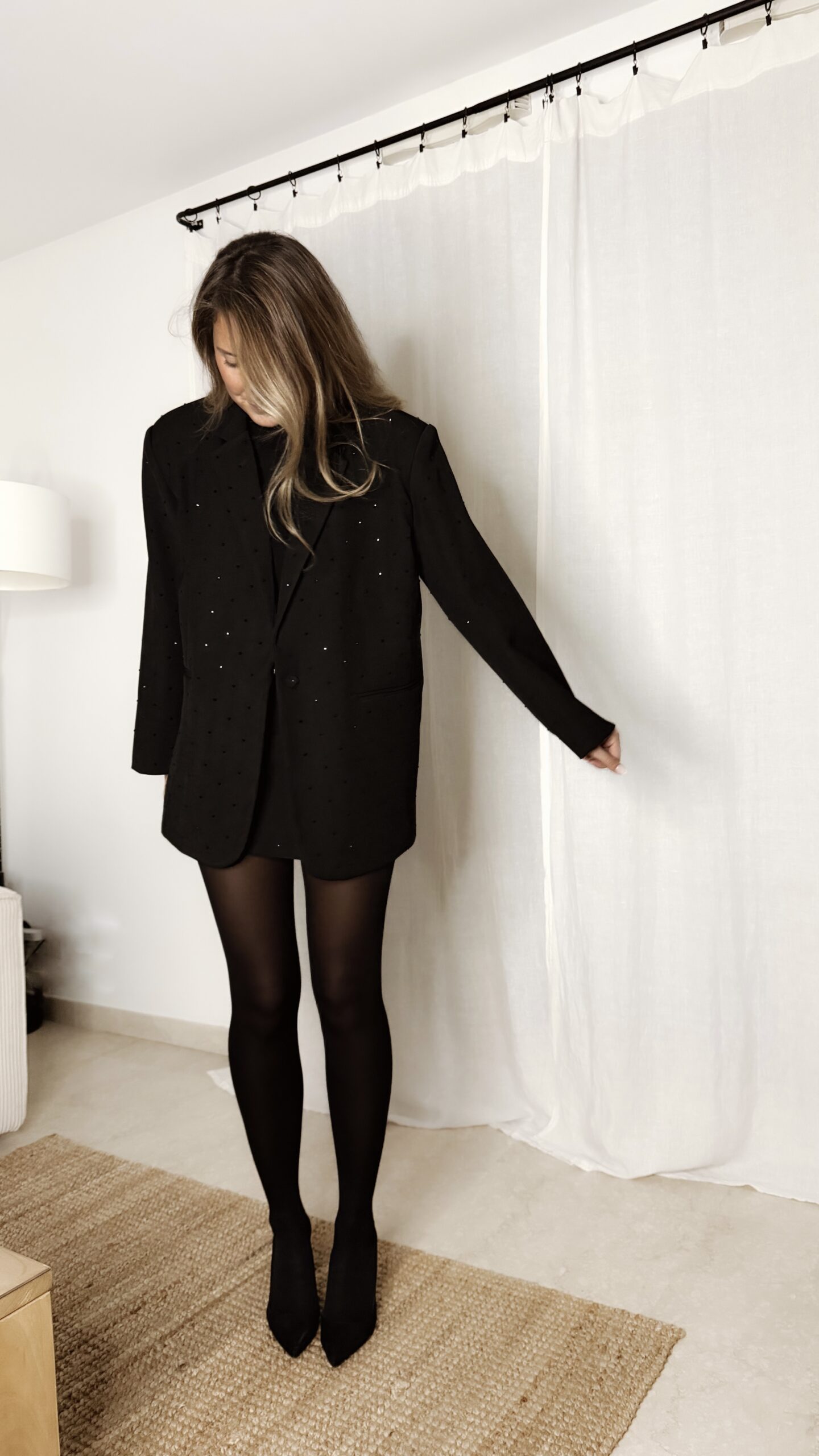Femme portant un blazer noir à strass avec collants noirs et escarpins, tenue élégante et chic de soirée.