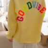 Sweat jaune à coupe ample, vu de dos, avec l’inscription brodée multicolore « GOOD VIBES ».