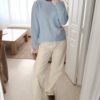Pull bleu ciel en maille douce avec poignets en dentelle, porté avec un pantalon clair