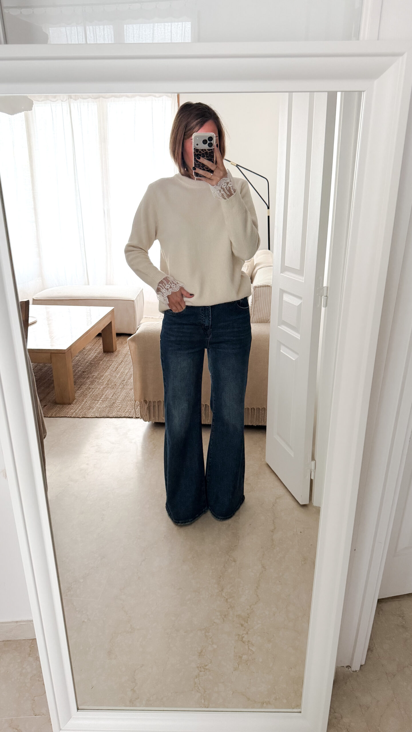 Jean flare bleu foncé avec un pull maille ecru et ses finition poignet dentelle