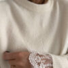 Pull ecru en maille douce avec poignets en dentelle, porté avec un pantalon clair