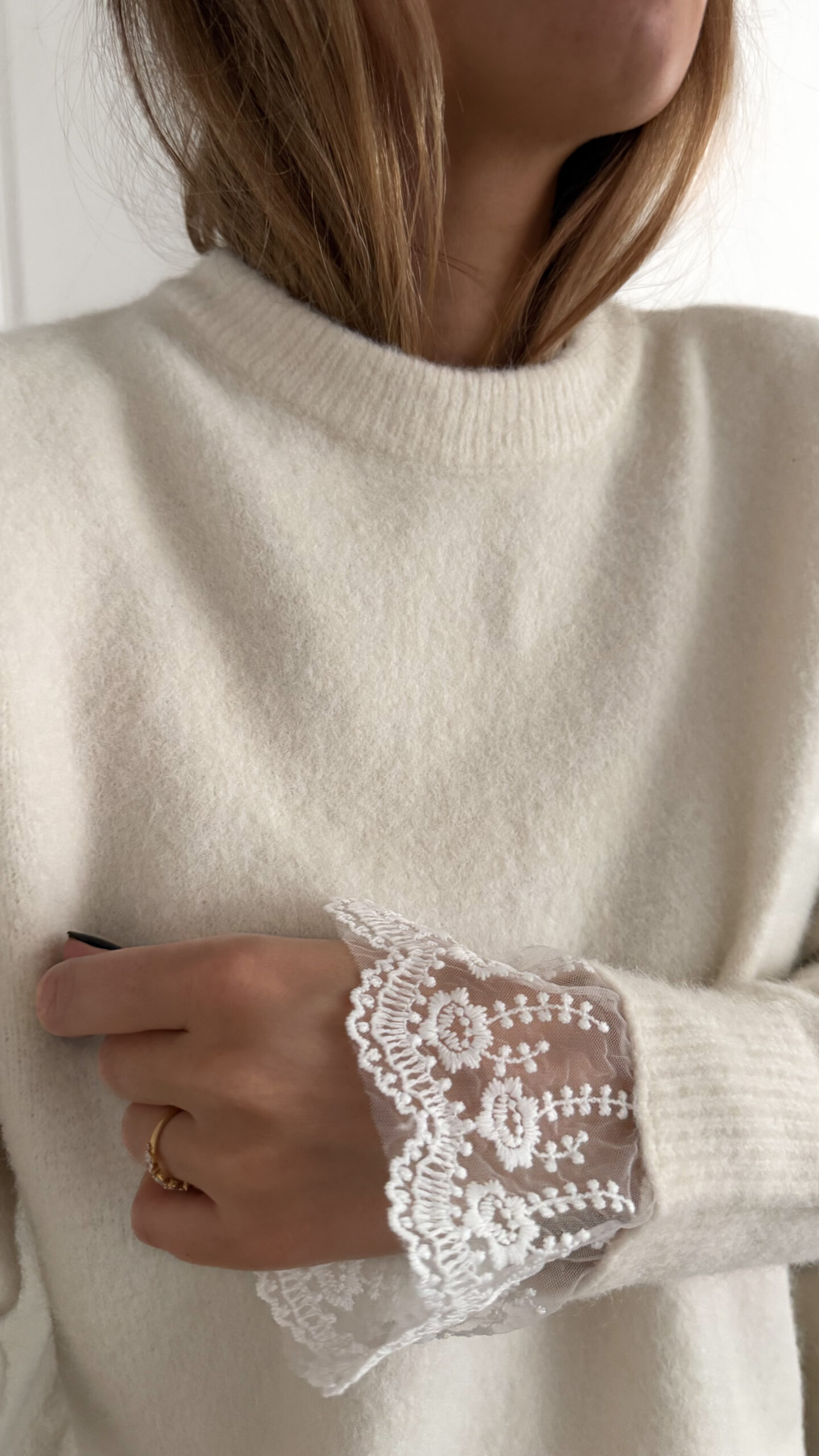 Pull ecru en maille douce avec poignets en dentelle, porté avec un pantalon clair
