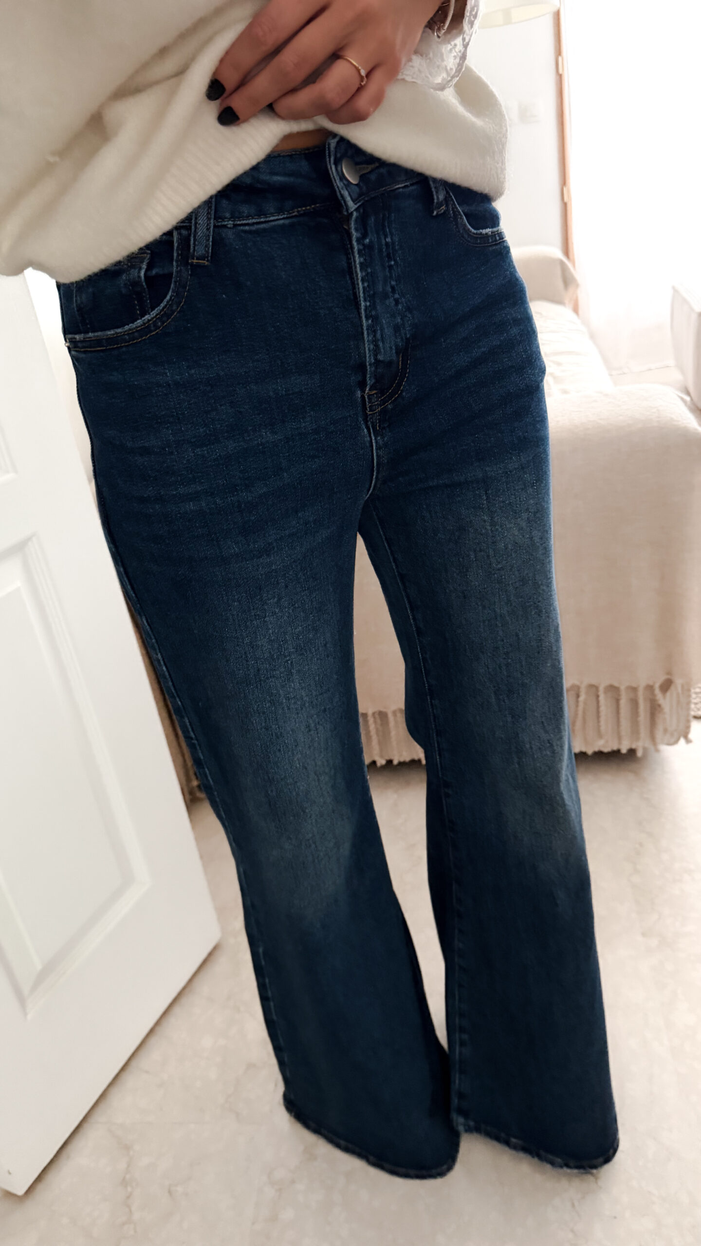 Jean flare bleu foncé avec un pull maille ecru et ses finition poignet dentelle