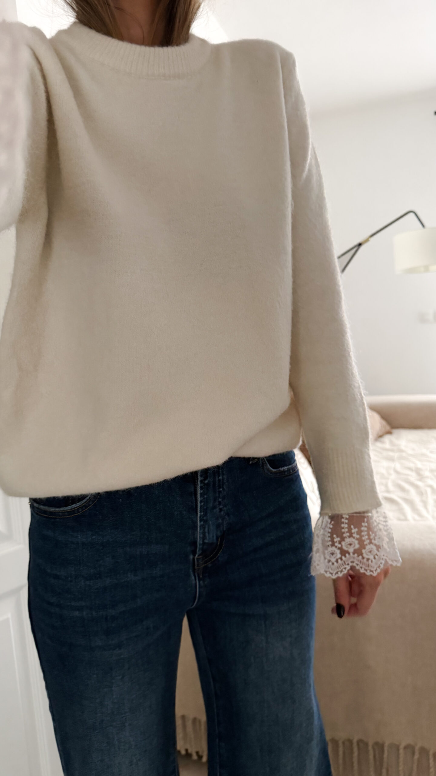 Jean flare bleu foncé avec un pull maille ecru et ses finition poignet dentelle