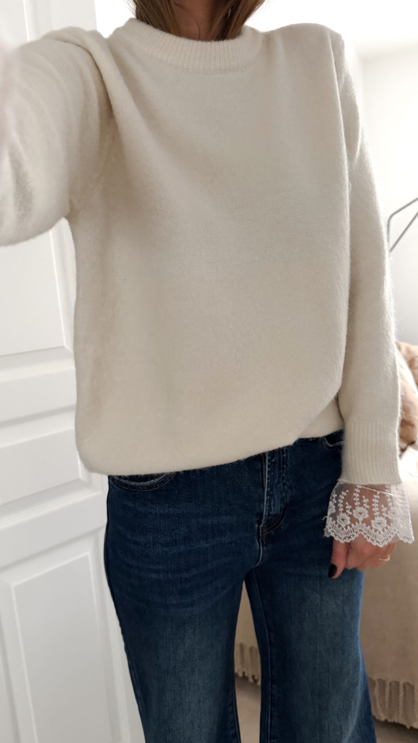 Pull ecru en maille douce avec poignets en dentelle, porté avec un pantalon clair