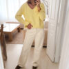 Pull jaune à col V, coupe droite, porté avec un pantalon clair, manches longues avec poignets volantés.