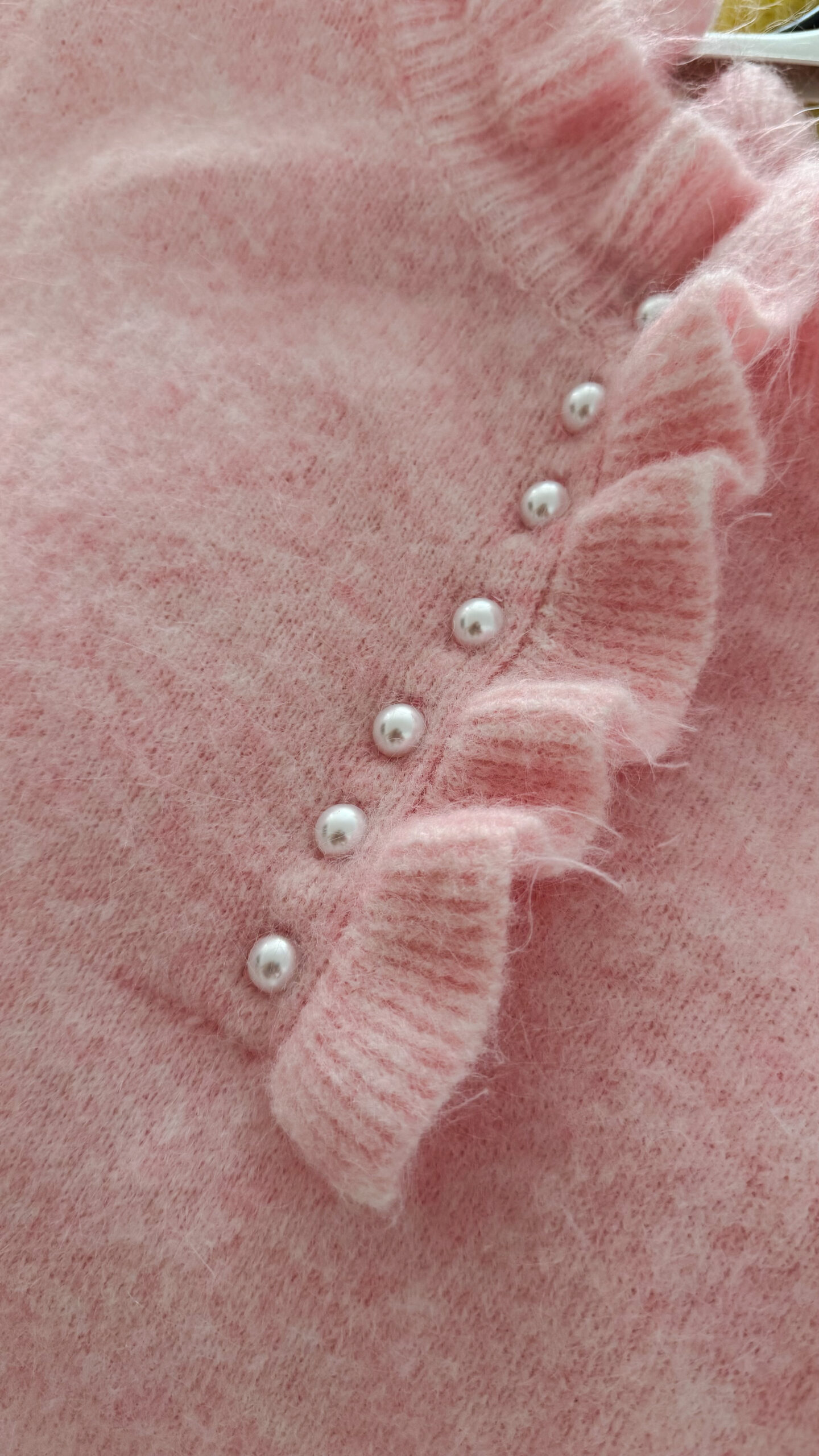 Pull rose en maille douce avec col volanté et boutons perles, porté avec un pantalon clair