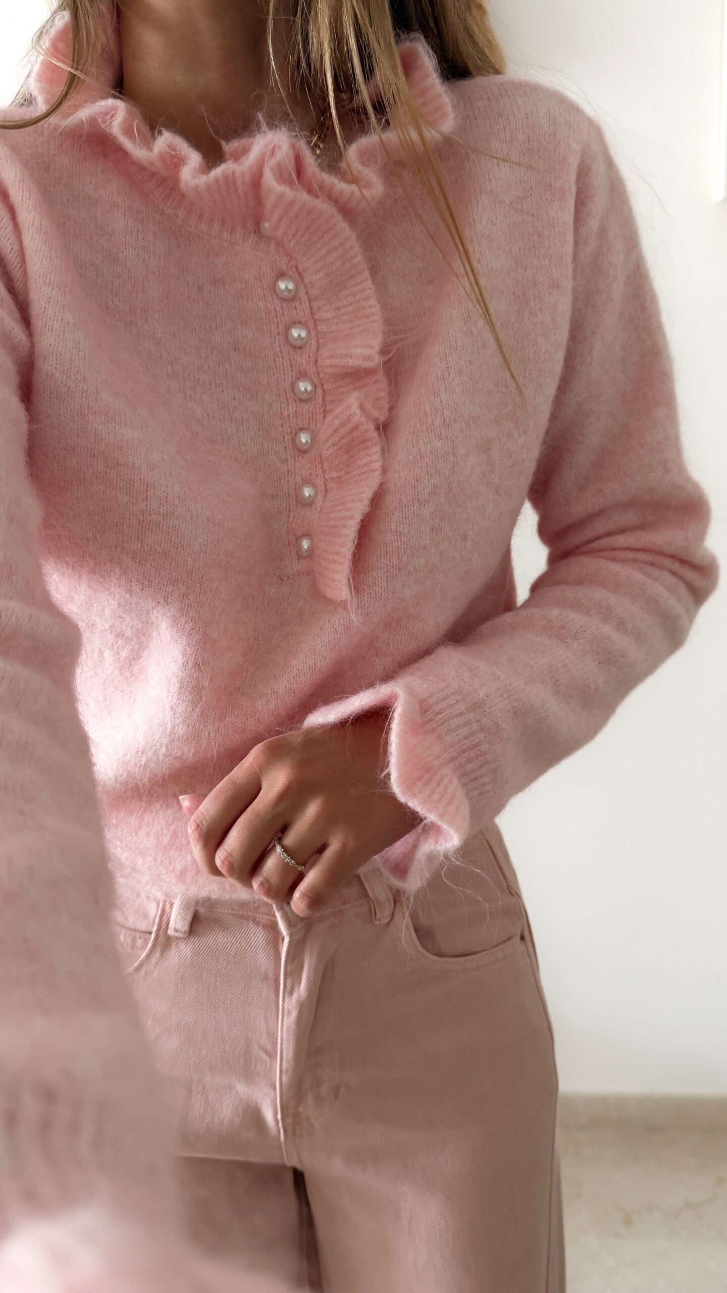 Pull rose en maille douce avec col volanté et boutons perles, porté avec un pantalon clair