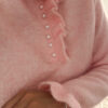 Pull rose en maille douce avec col volanté et boutons perles, porté avec un pantalon clair