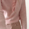 Pull rose en maille douce avec col volanté et boutons perles, porté avec un pantalon clair