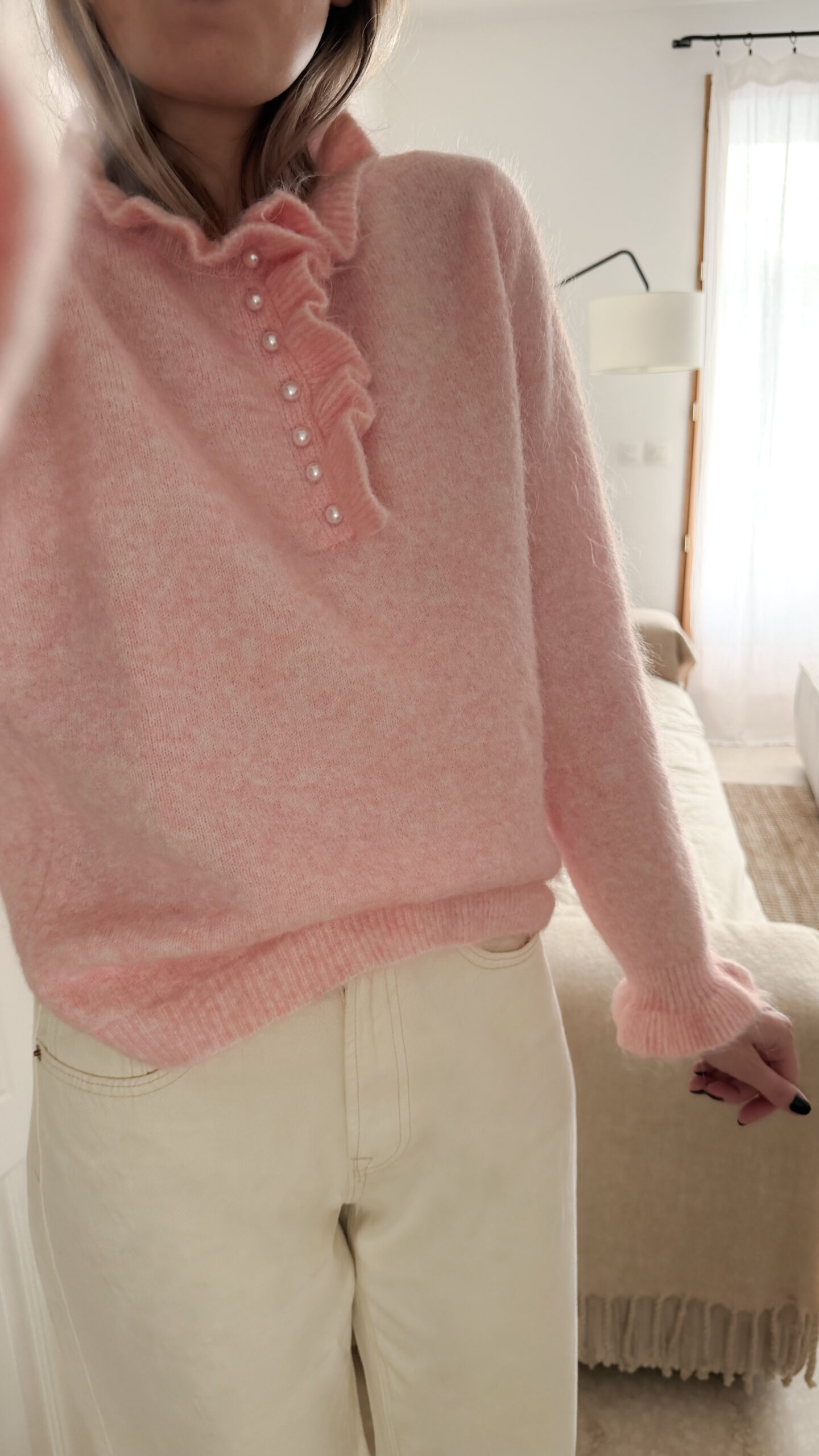 Pull rose en maille douce avec col volanté et boutons perles, porté avec un pantalon clair