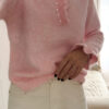 Pull rose en maille douce avec col volanté et boutons perles, porté avec un pantalon clair