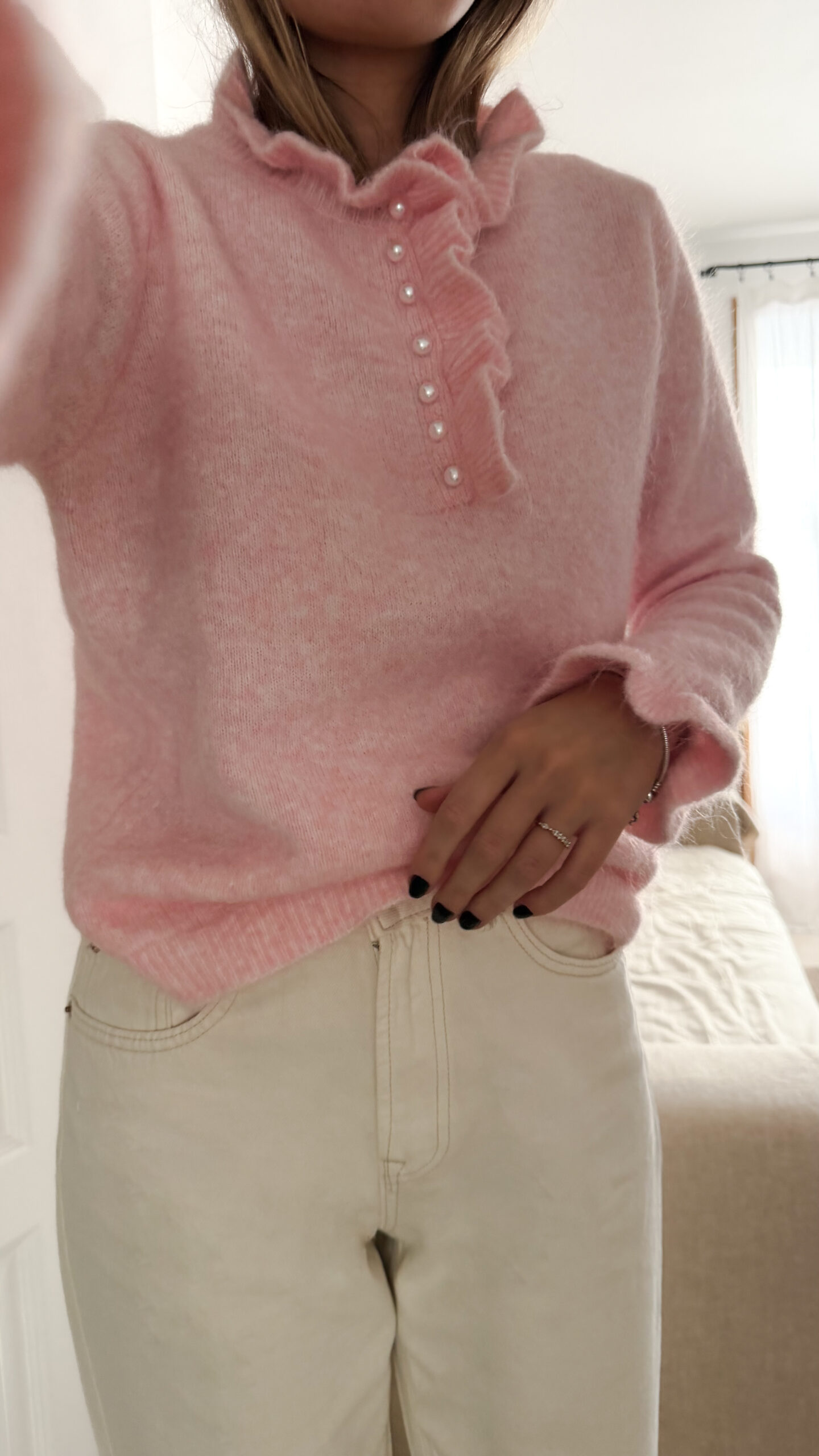 Pull rose en maille douce avec col volanté et boutons perles, porté avec un pantalon clair