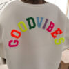 Sweat blanc à coupe ample, vu de dos, avec l’inscription brodée multicolore « GOOD VIBES ».
