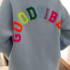 Sweat bleu ciel à coupe ample, vu de dos, avec l’inscription brodée multicolore « GOOD VIBES ».