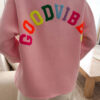 Sweat rose à coupe ample, vu de dos, avec l’inscription brodée multicolore « GOOD VIBES ».