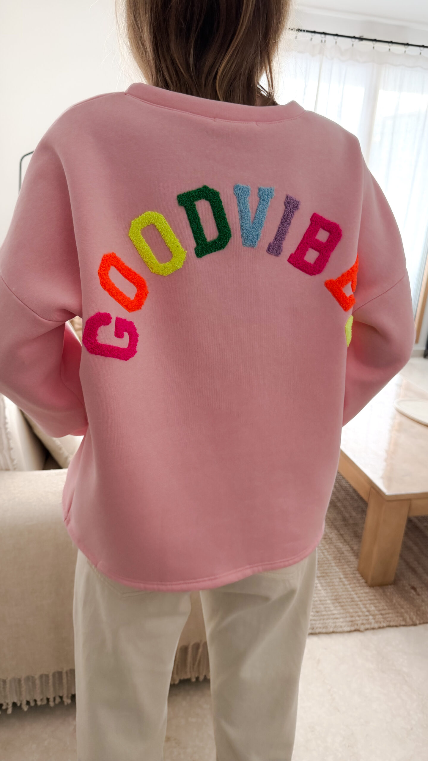 Sweat rose à coupe ample, vu de dos, avec l’inscription brodée multicolore « GOOD VIBES ».