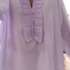 Blouse femme lilas pastel avec plastron plissé, boutons et manches longues, portée avec un bas clair.