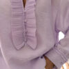 Blouse femme lilas pastel avec plastron plissé, boutons et manches longues, portée avec un bas clair.