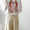 Chemise blanche femme avec broderie de deux perroquets colorés dans le dos, portée avec un pantalon jaune pâle