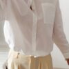 Chemise blanche femme avec broderie de deux perroquets colorés dans le dos, portée avec un pantalon jaune pâle