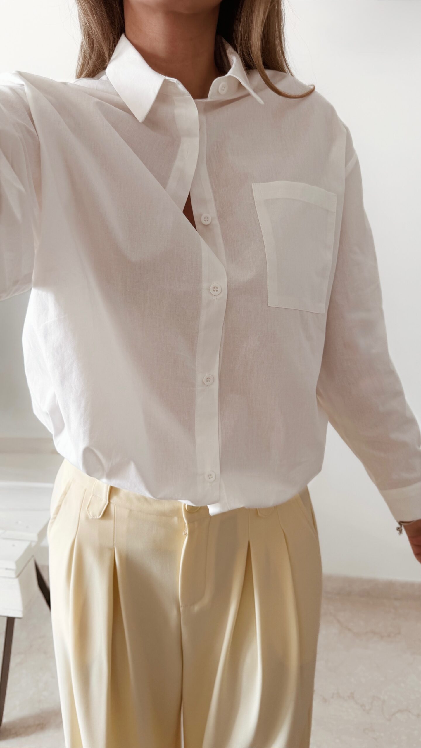 Chemise blanche femme avec broderie de deux perroquets colorés dans le dos, portée avec un pantalon jaune pâle
