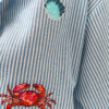 Chemise femme rayée bleue et blanche avec broderies marines colorées (flamant rose, crabe, étoile de mer et coquillages)