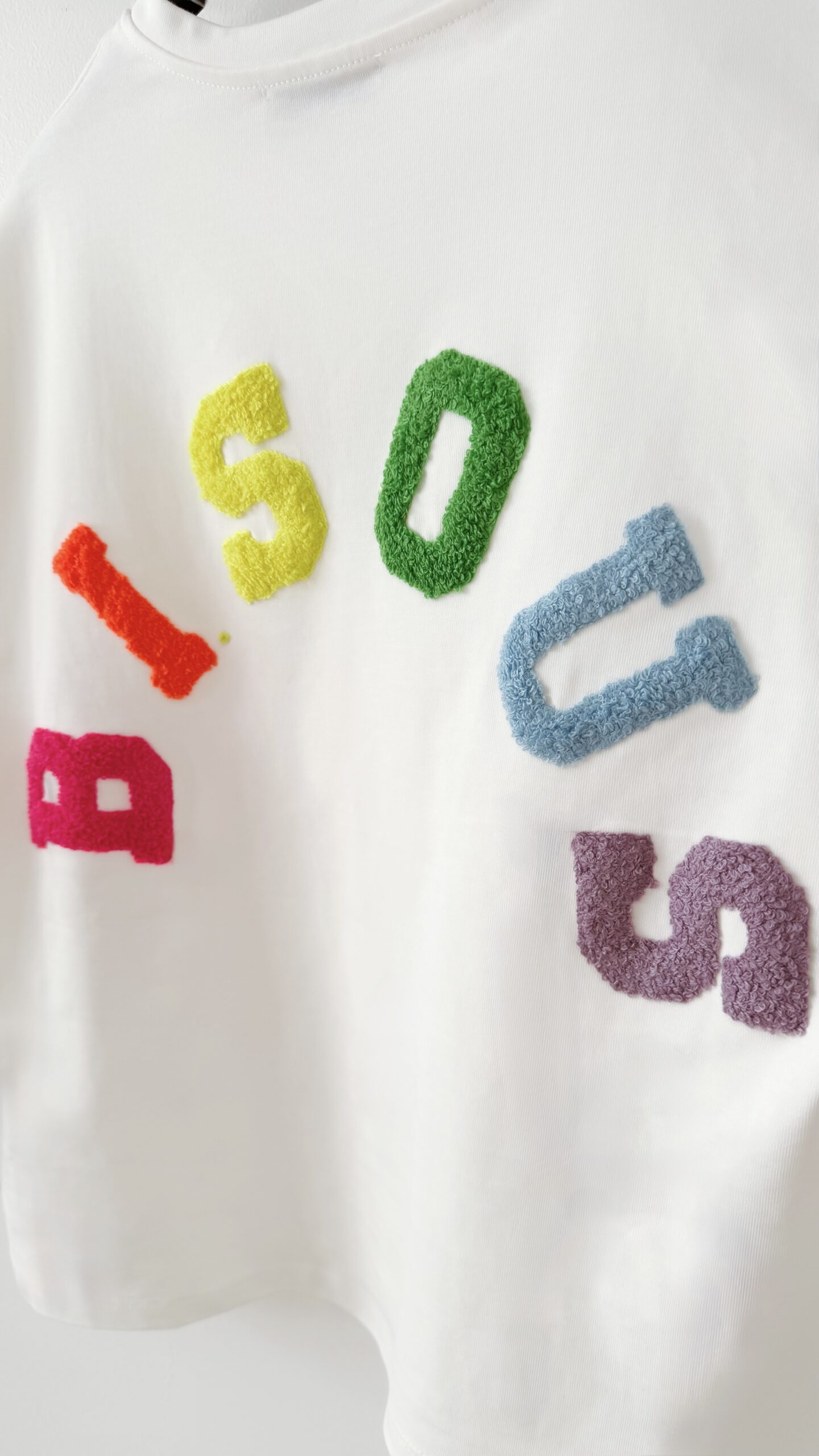 Femme vue de dos portant un ensemble blanc avec un t-shirt oversize orné de lettres colorées en relief