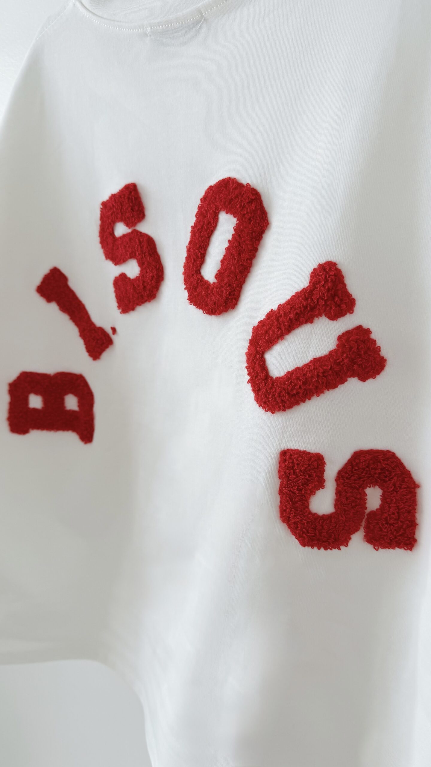 Femme vue de dos portant un ensemble blanc avec un t-shirt oversize orné de lettres rouge en relief