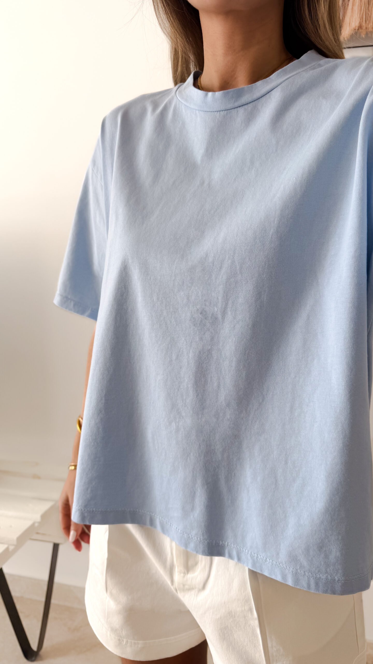 Femme portant un t-shirt oversize bleu clair avec un short blanc taille haute
