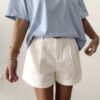 Femme portant un t-shirt oversize bleu clair avec un short blanc taille haute