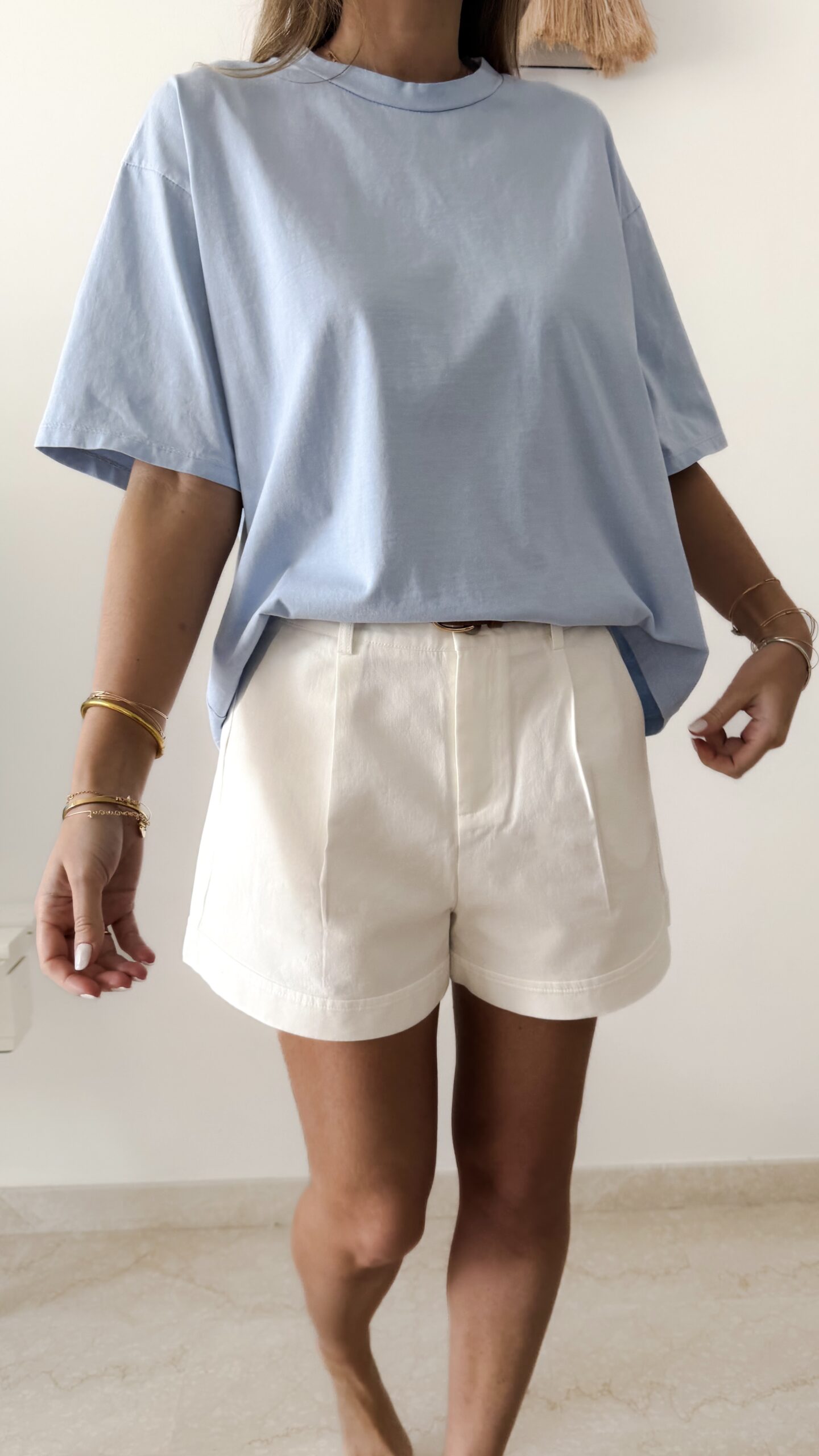 Femme portant un t-shirt oversize bleu clair avec un short blanc taille haute