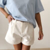 Femme portant un t-shirt oversize bleu clair avec un short blanc taille haute