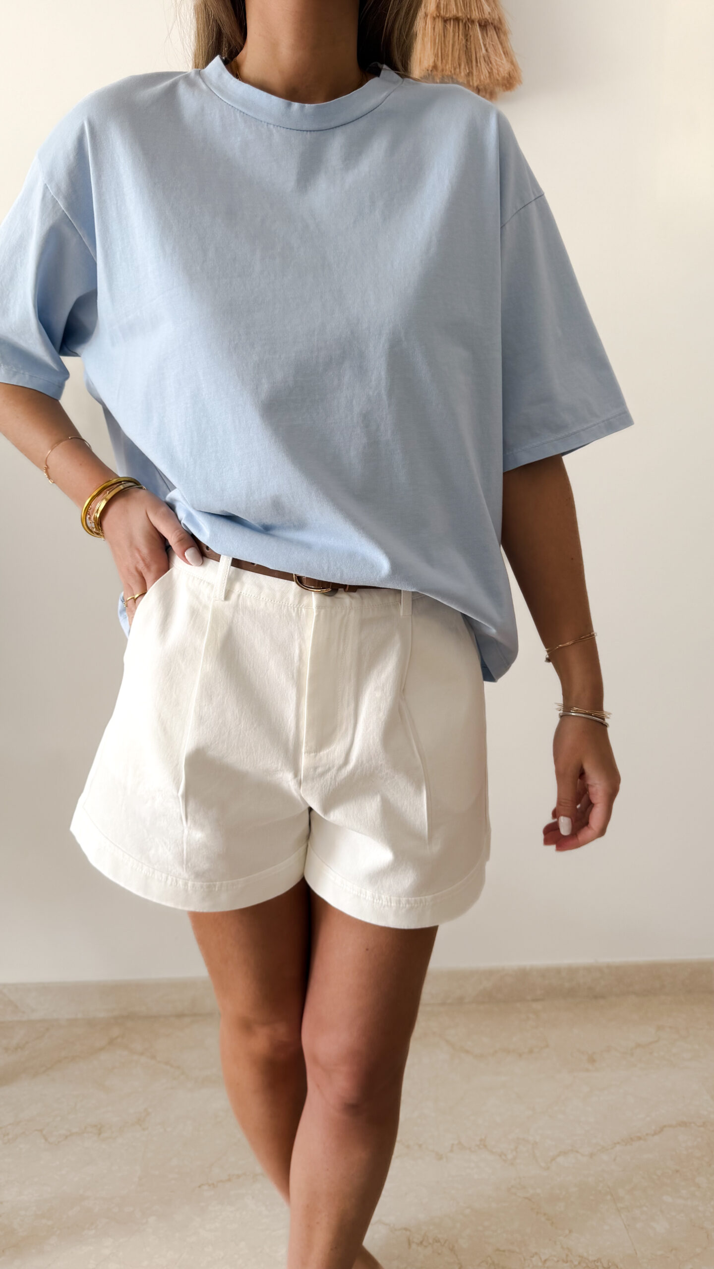 Femme portant un t-shirt oversize bleu clair avec un short blanc taille haute