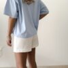 Femme portant un t-shirt oversize bleu clair avec un short blanc taille haute
