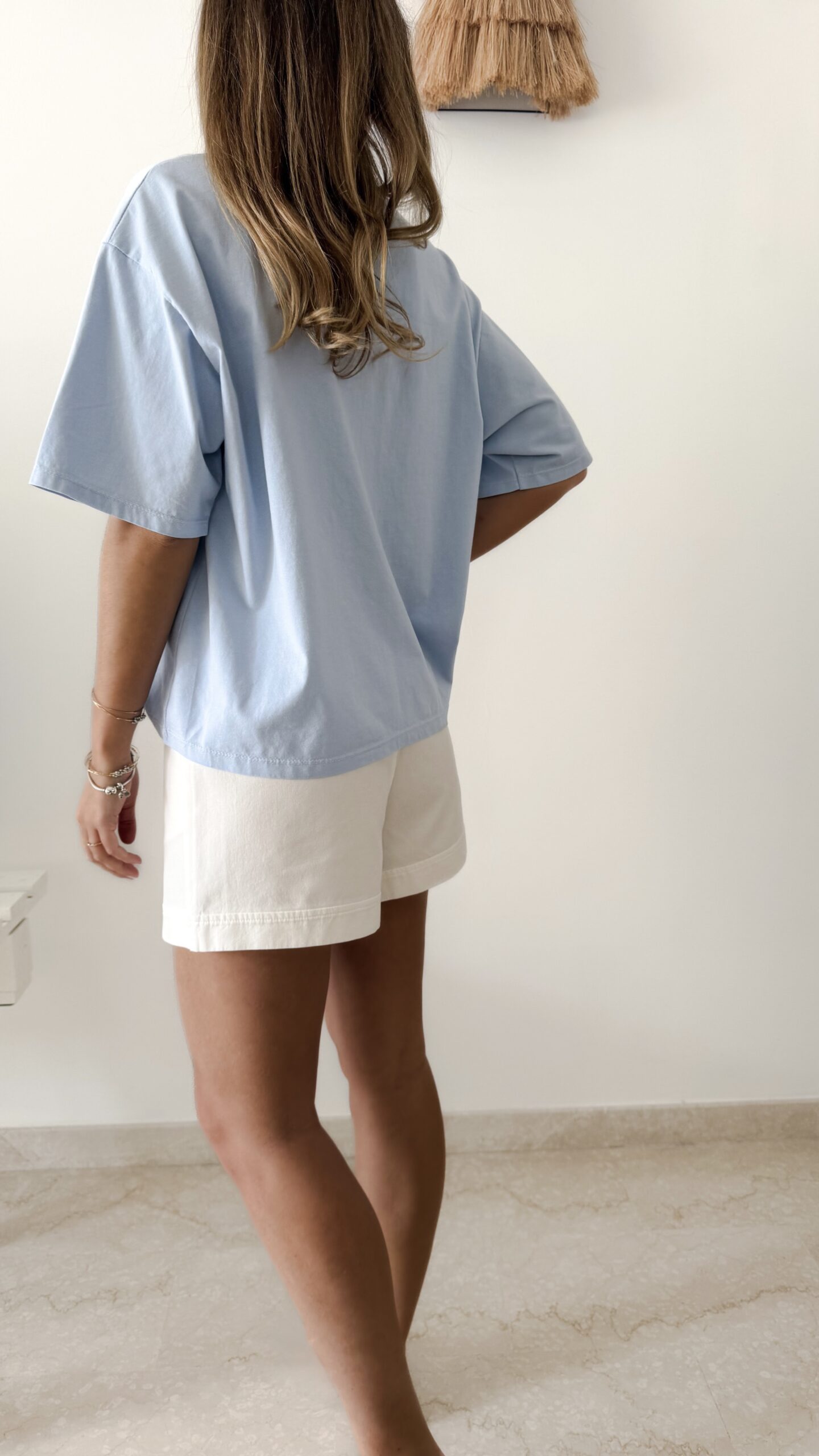Femme portant un t-shirt oversize bleu clair avec un short blanc taille haute