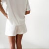 Femme portant un t-shirt blanc avec imprimé coucher de soleil et palmiers en sequins