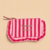 Collection de pochettes colorées à rayures et motifs vichy avec volants décoratifs et messages brodés, présentées sur un fond beige dans un style féminin et tendance.