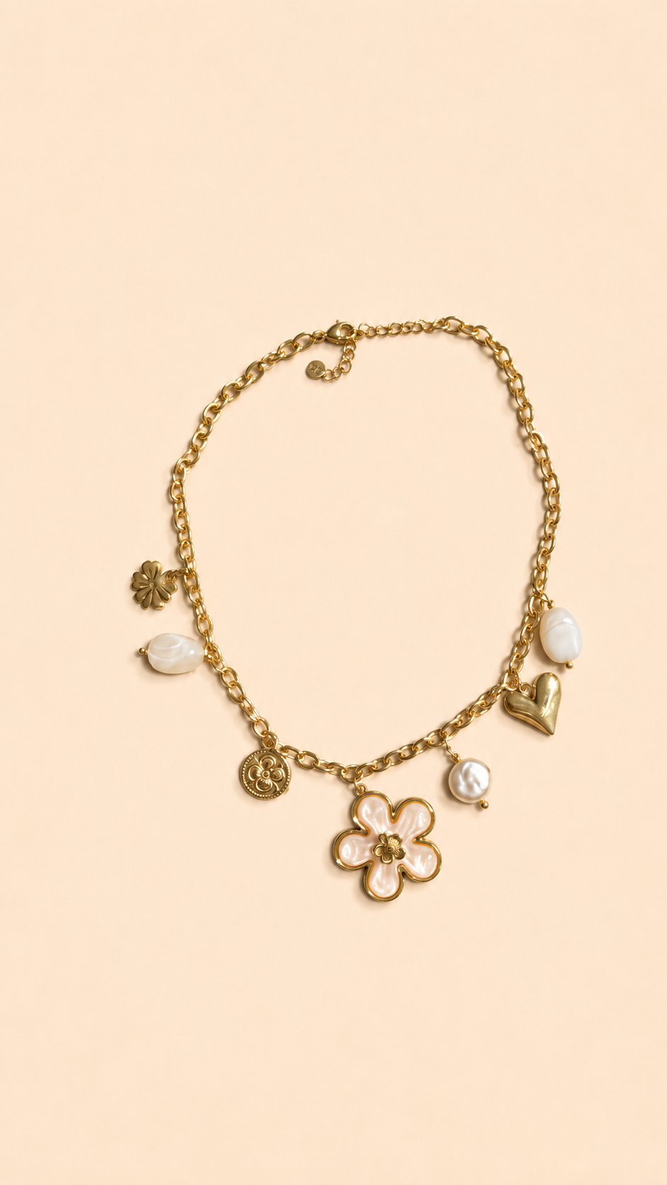 Collier chaîne dorée avec pendentif fleur blanche, perle et charms dorés porté sur peau bronzée avec tenue estivale.