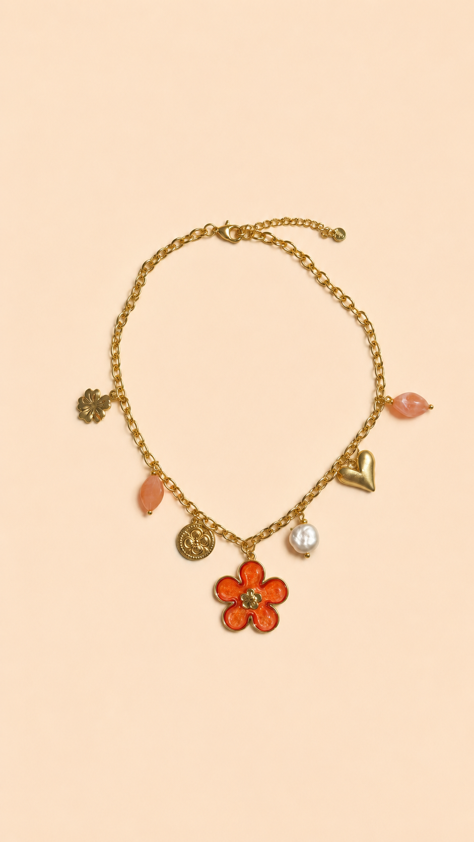 Collier chaîne dorée avec pendentif fleur corail, perle et charms colorés porté sur peau bronzée avec tenue estivale.