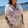 Ensemble femme bohème chic bleu à motif cachemire composé d'une chemise fluide et d'un short léger, porté sur une plage en été.