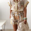 Ensemble femme bohème chic beige à motif cachemire composé d'une chemise fluide et d'un short léger, porté sur une plage en été.