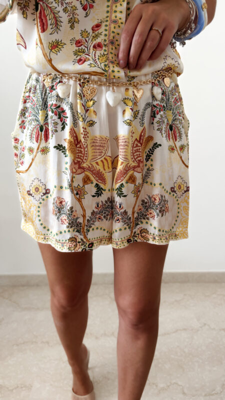 Ensemble femme bohème chic beige à motif cachemire composé d'une chemise fluide et d'un short léger, porté sur une plage en été.