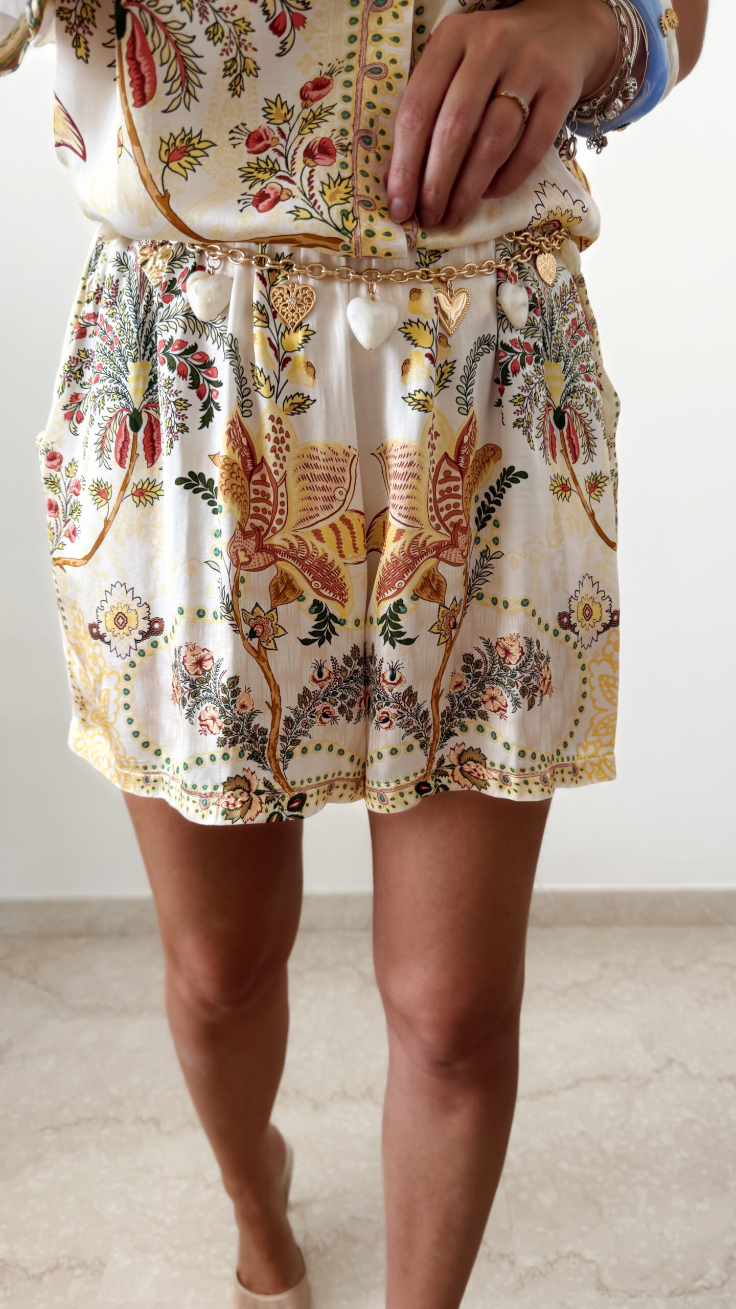 Ensemble femme bohème chic beige à motif cachemire composé d'une chemise fluide et d'un short léger, porté sur une plage en été.
