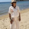 Femme portant l'ensemble Zoé composé d'une blouse rayée beige brodée et d'un pantalon fluide rayé beige sur une plage ensoleillée.
