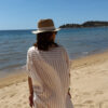 Femme portant l'ensemble Zoé composé d'une blouse rayée beige brodée et d'un pantalon fluide rayé beige sur une plage ensoleillée.