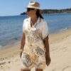 Ensemble femme bohème chic beige à motif cachemire composé d'une chemise fluide et d'un short léger, porté sur une plage en été.