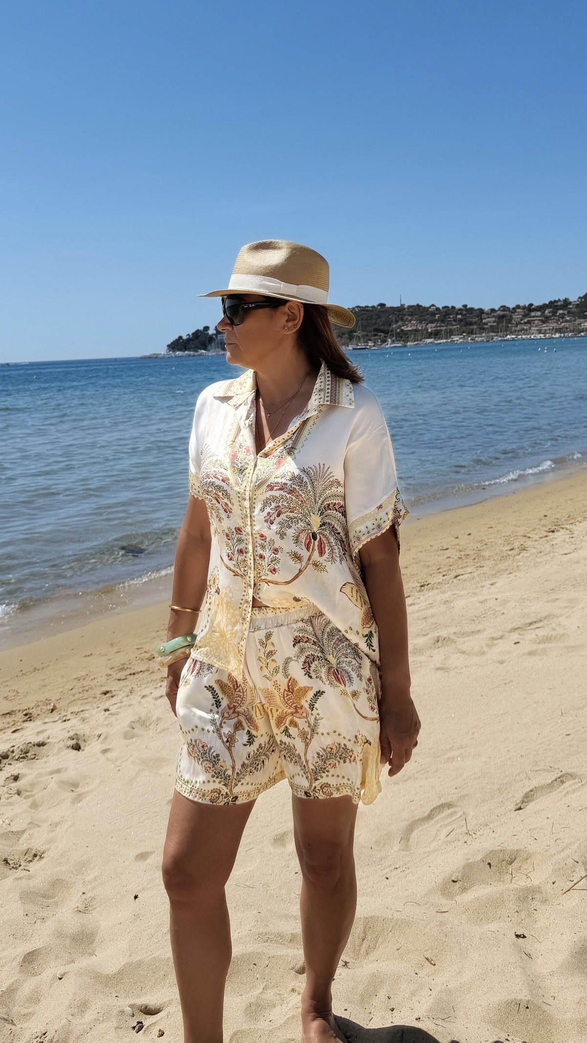 Ensemble femme bohème chic beige à motif cachemire composé d'une chemise fluide et d'un short léger, porté sur une plage en été.