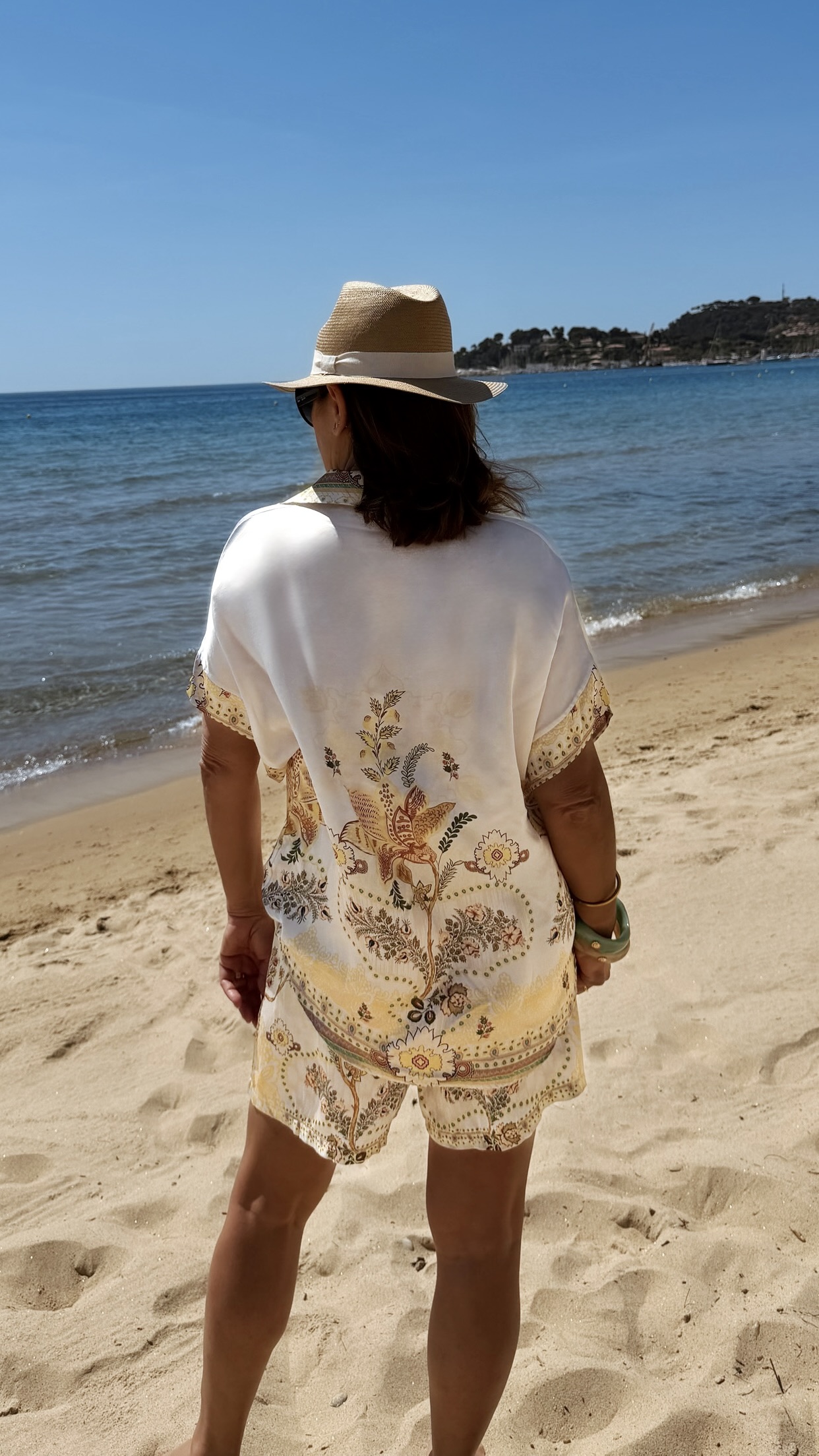 Ensemble femme bohème chic beige à motif cachemire composé d'une chemise fluide et d'un short léger, porté sur une plage en été.