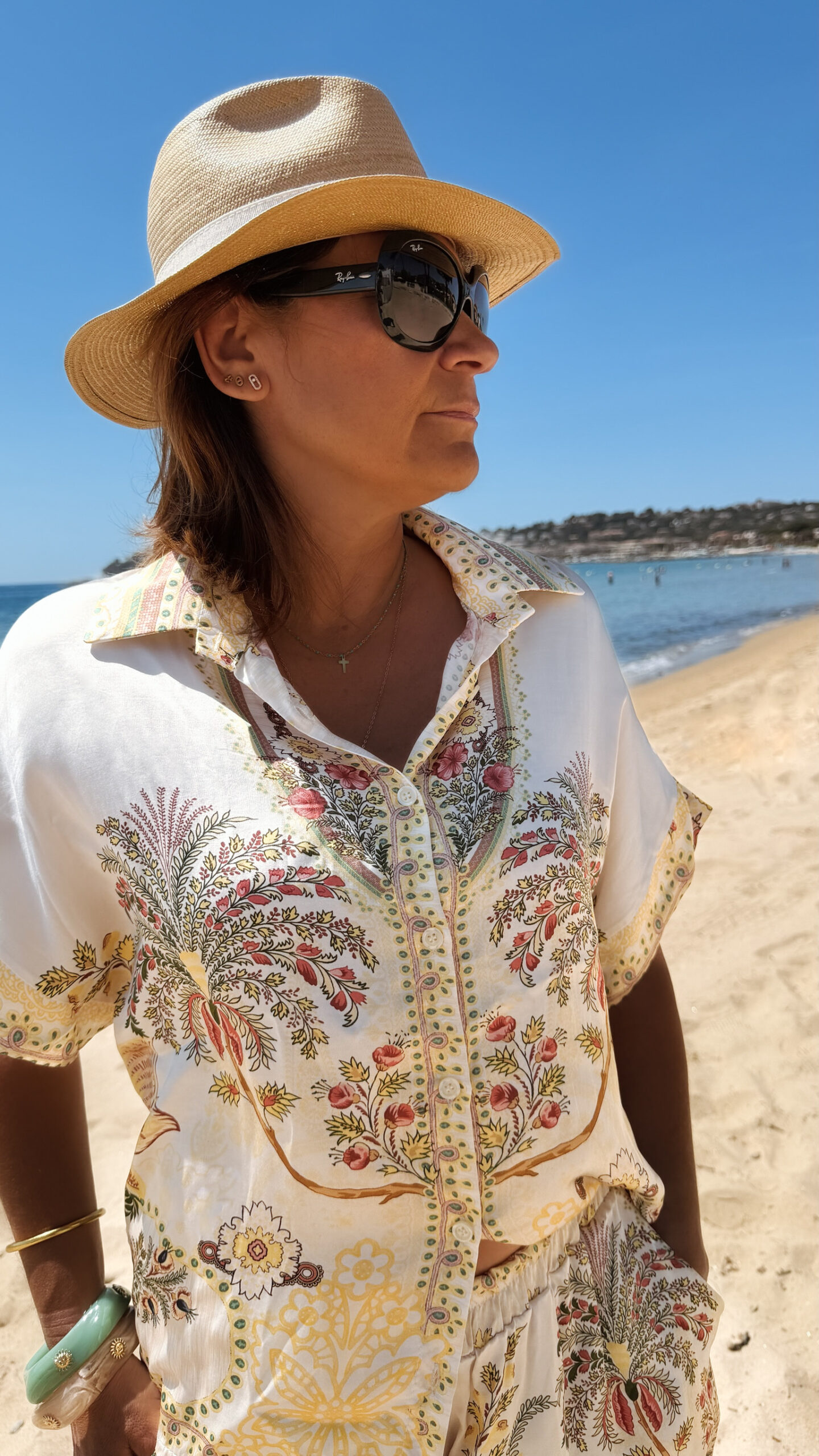 Ensemble femme bohème chic beige à motif cachemire composé d'une chemise fluide et d'un short léger, porté sur une plage en été.